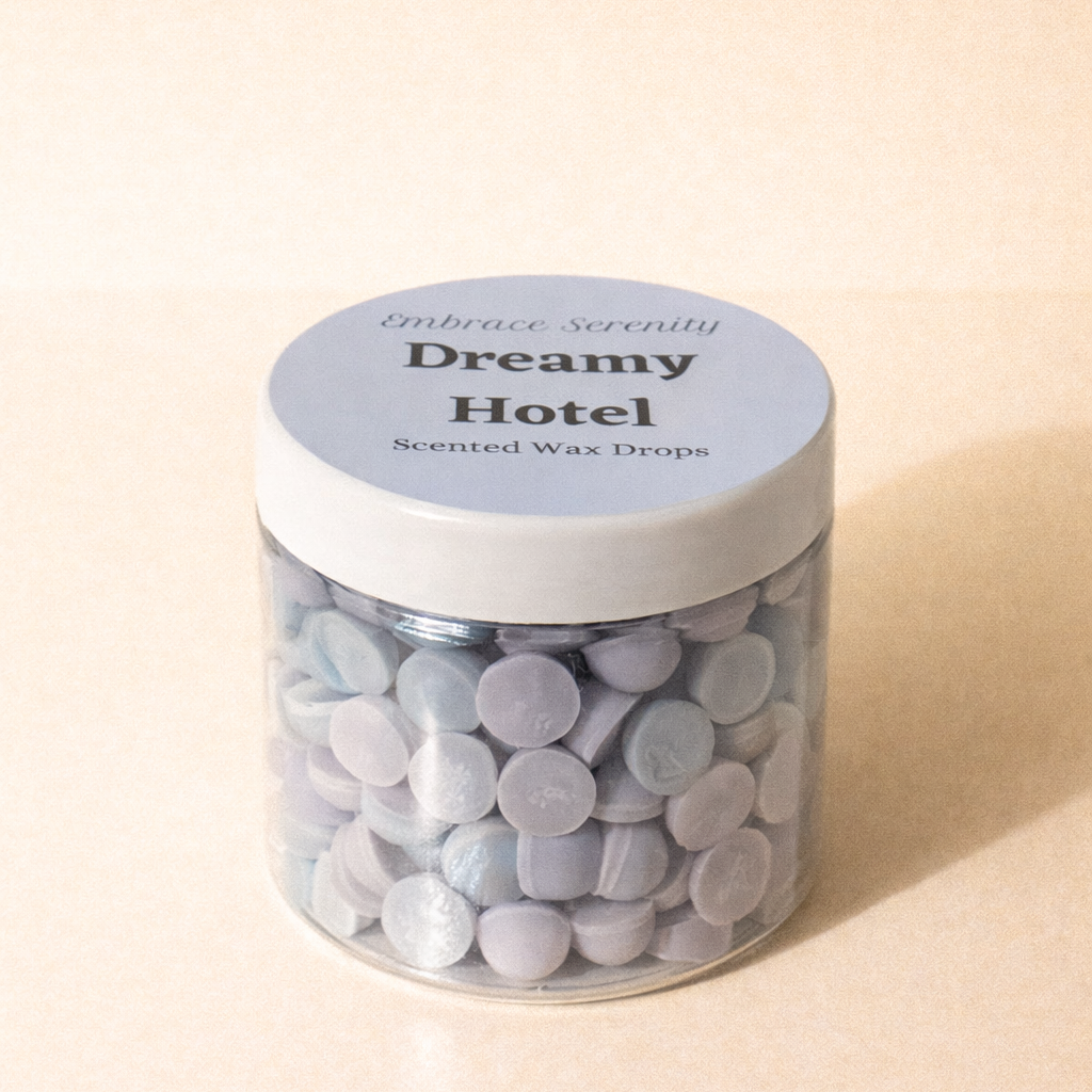 Jar of scented wax drops labeled 'Dreamy Hotel' on a beige background